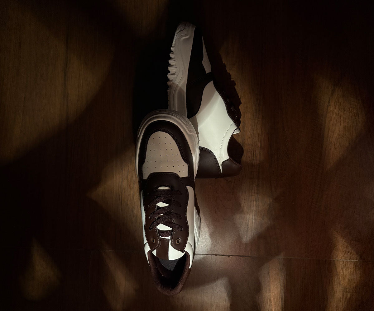 Pair of black and white Hitoes height increasing sneakers on a wooden floor